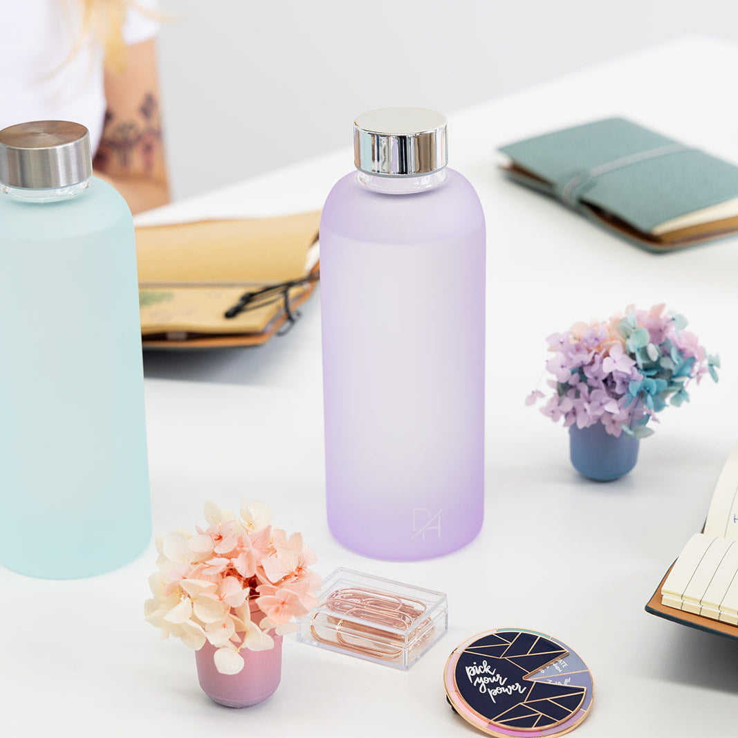 Two frosted glass water bottles on a desk with decorative items