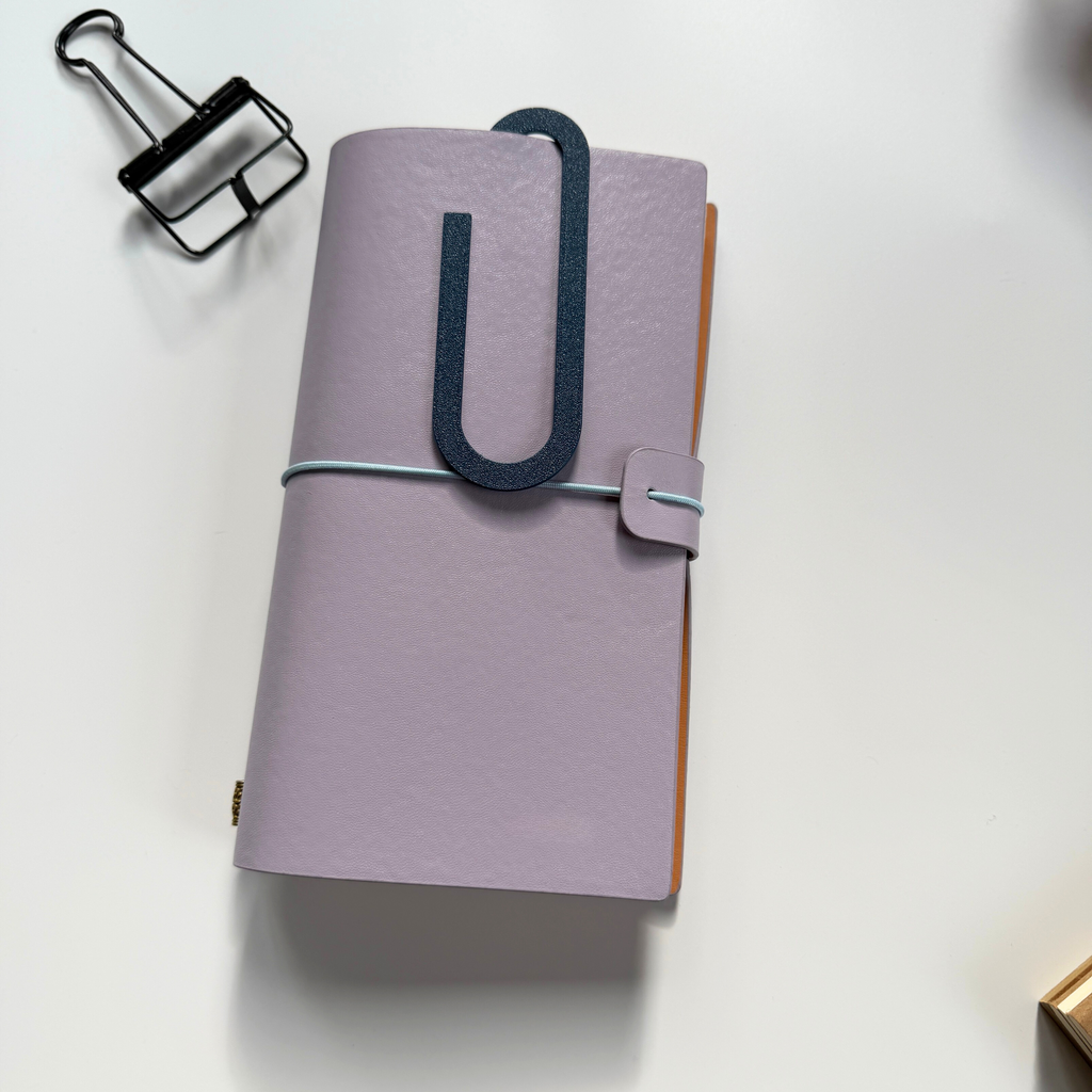 Purple planner with a black clip on a white background