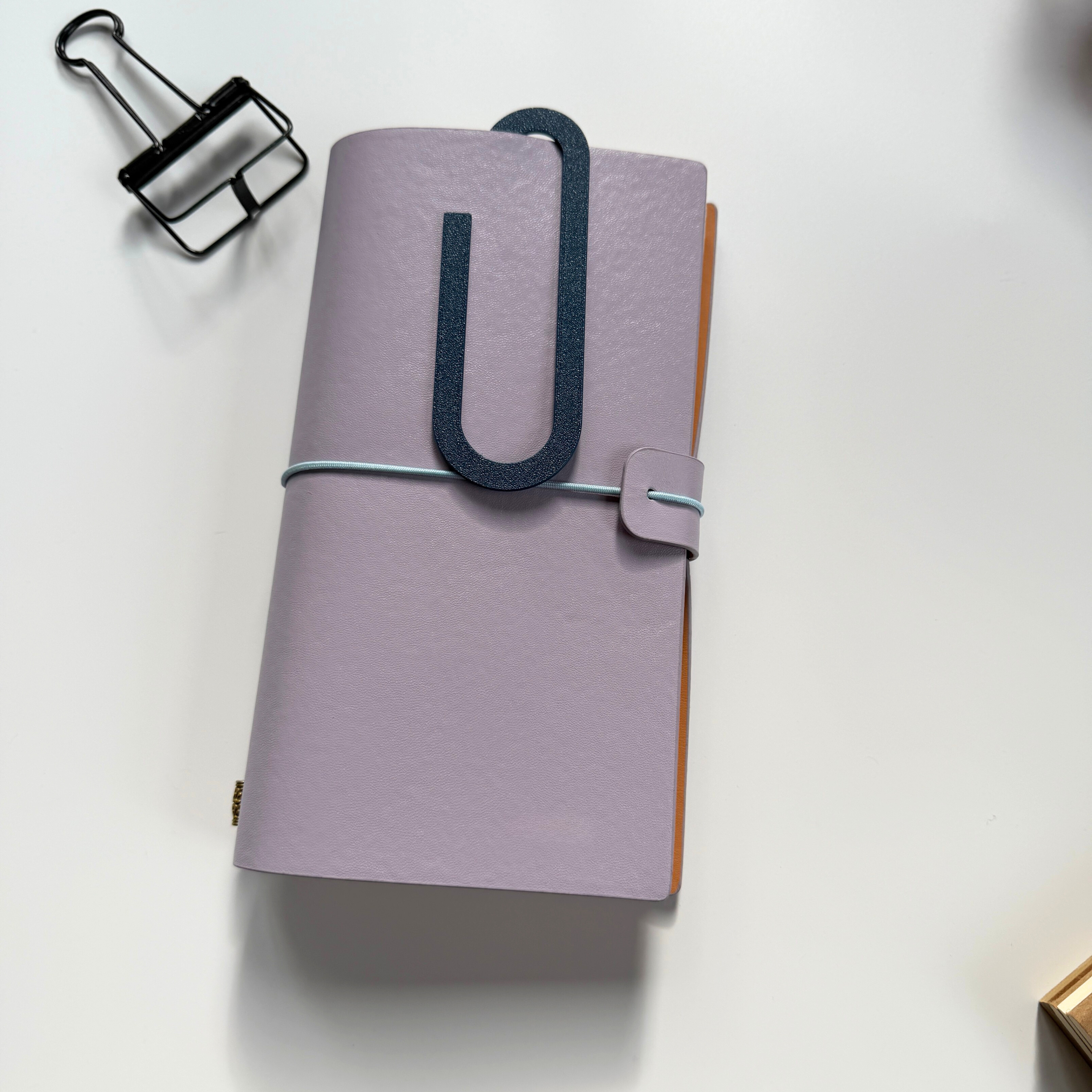 Purple planner with a black clip on a white background