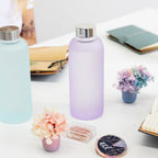 Two frosted glass water bottles on a desk with decorative items