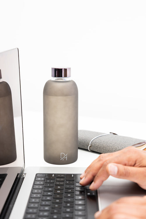 Clear glass water bottle with frosted finish and leak-proof metal cap